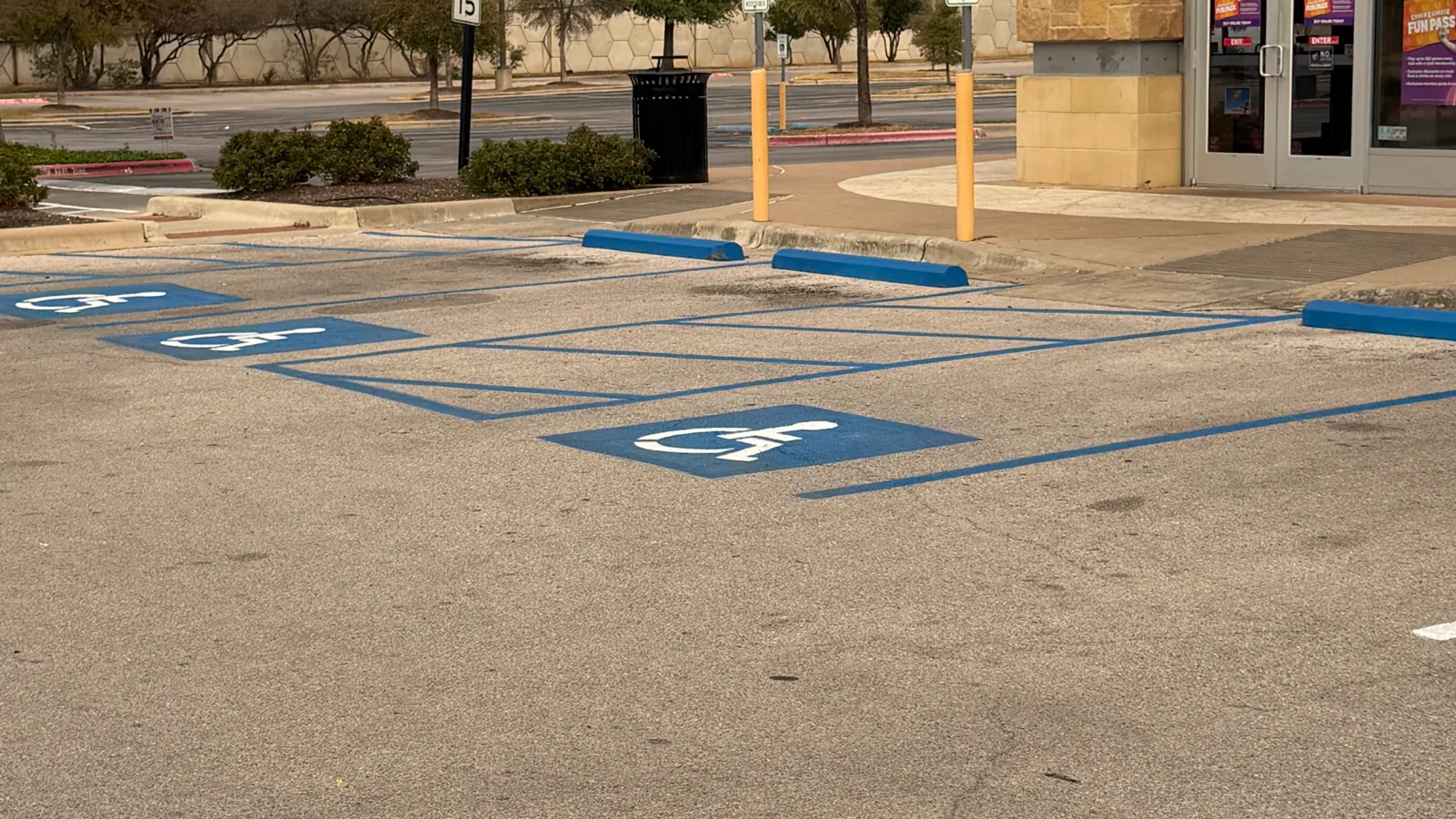 Freshly painted blue accessible parking stalls with wheelchair symbols at a storefront.