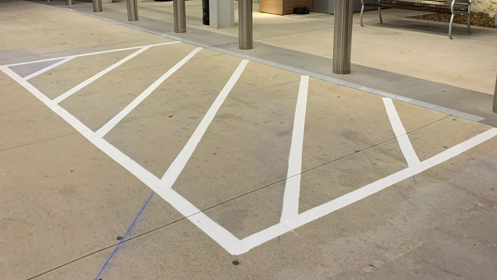 Fresh white crosshatch no-parking markings laid out at a covered hospital entrance.