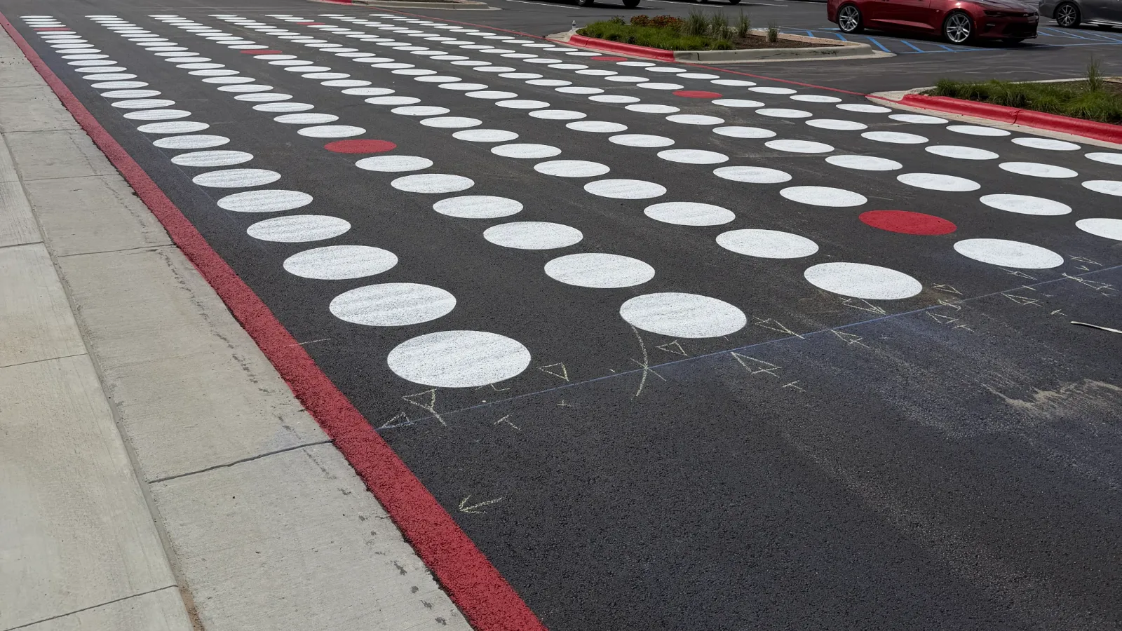 A Stripe-It-Up crosswalk: rows of fresh white and red painted dots across a new asphalt drive.