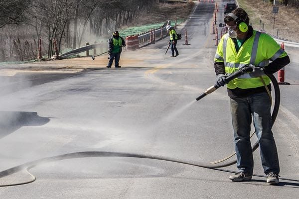 Sandblasting being used on a highway to remove old striping
